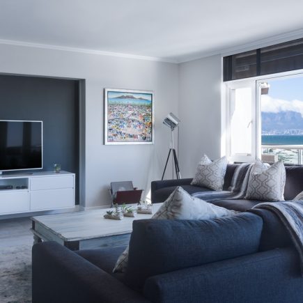 Salon avec canapé bleu marine, baie vitrée avec vue