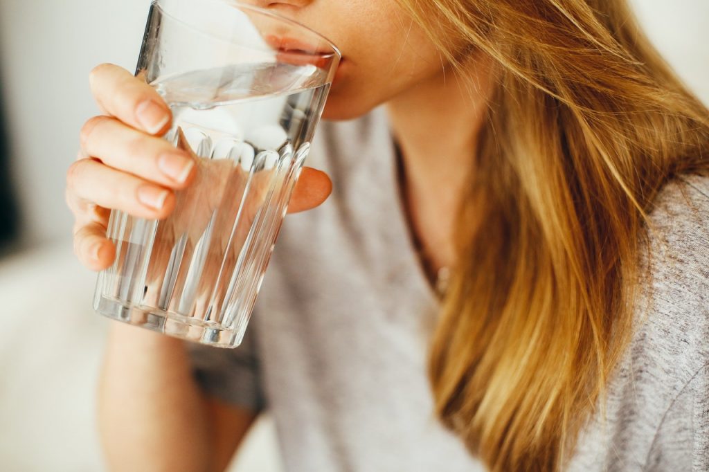 Femme blonde buvant un grand verre d'eau