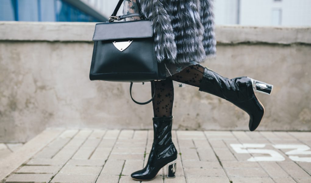 Femme portant un manteau de fourrure tenant un sac de luxe et portant des bottes à talon