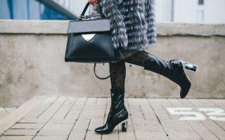 Femme portant un manteau de fourrure tenant un sac de luxe et portant des bottes à talon