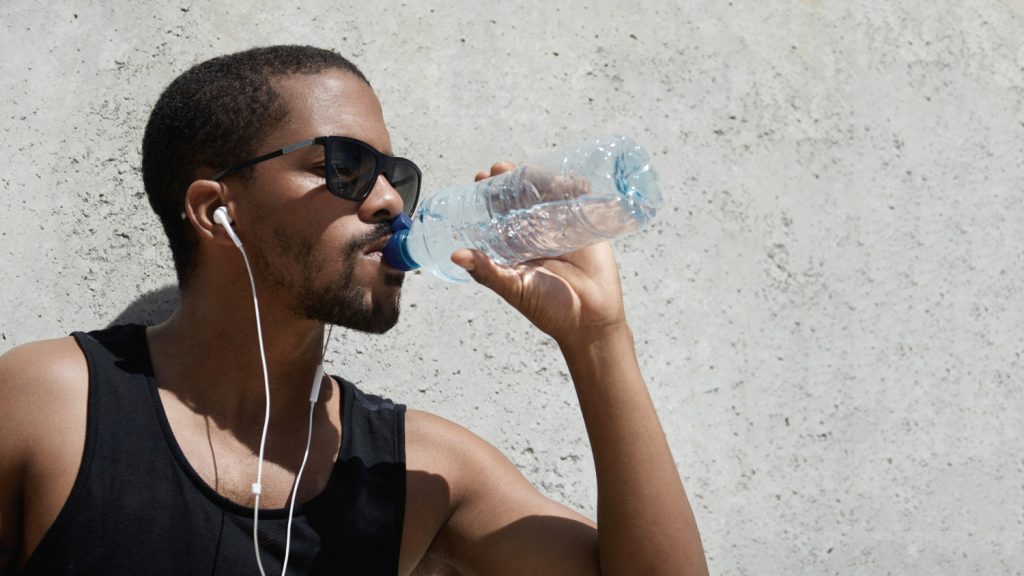 Homme écoutant de la musique et buvant de l'eau d'une bouteille